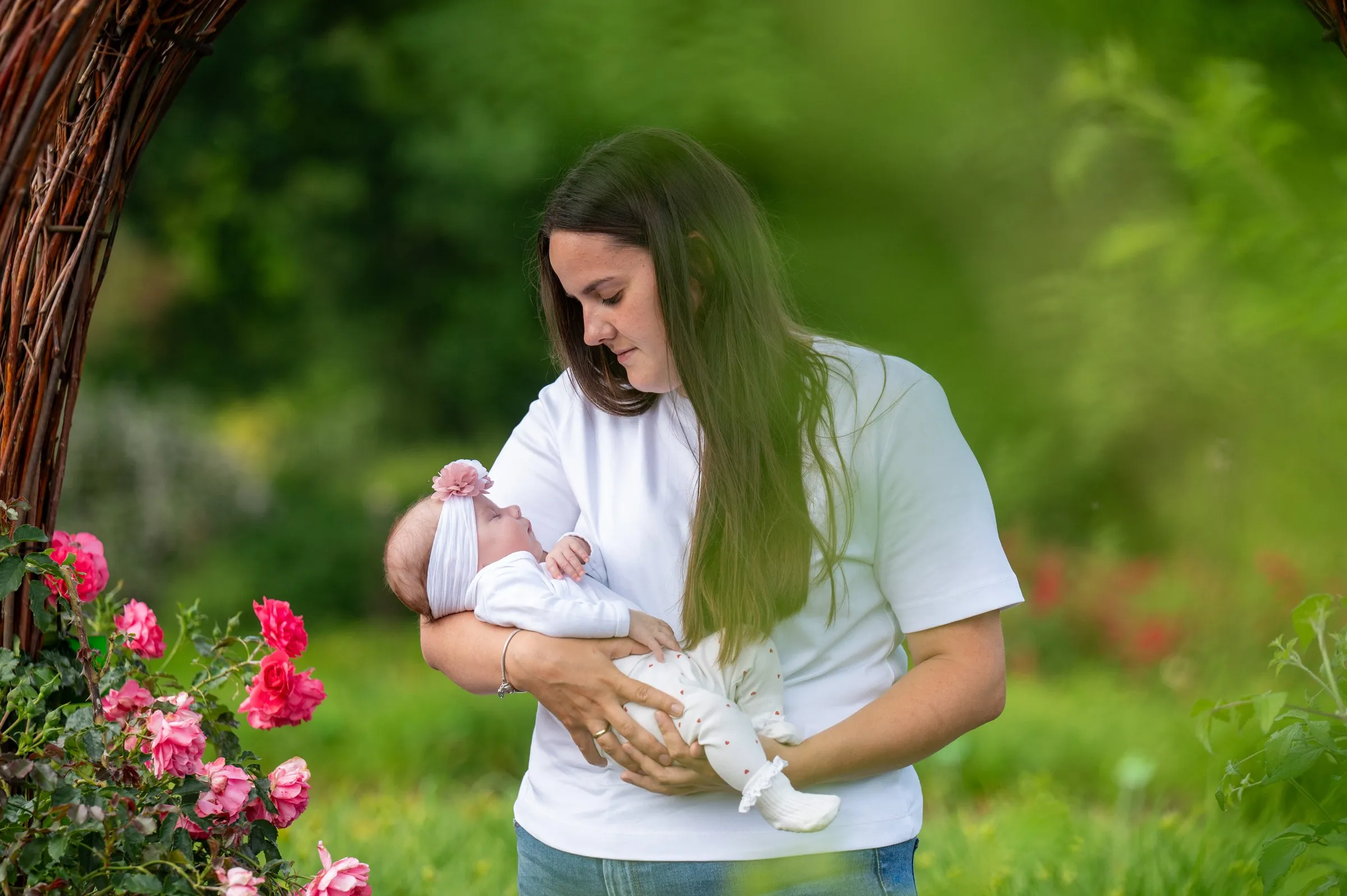 Mama z niemowlęciem na rękach wśród kwiatów