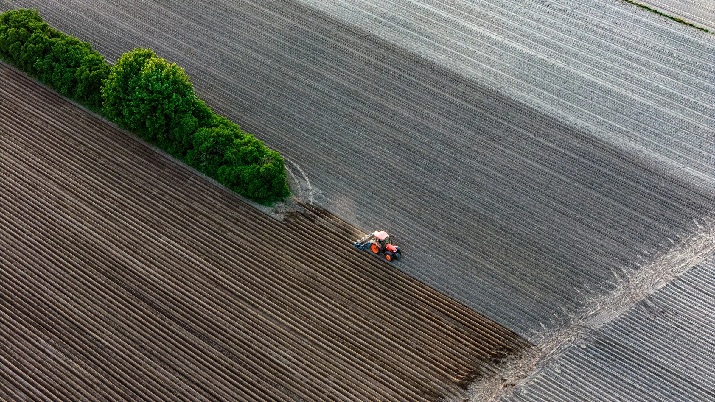 Traktor wśród pól — geometryczne zdjęcie z drona