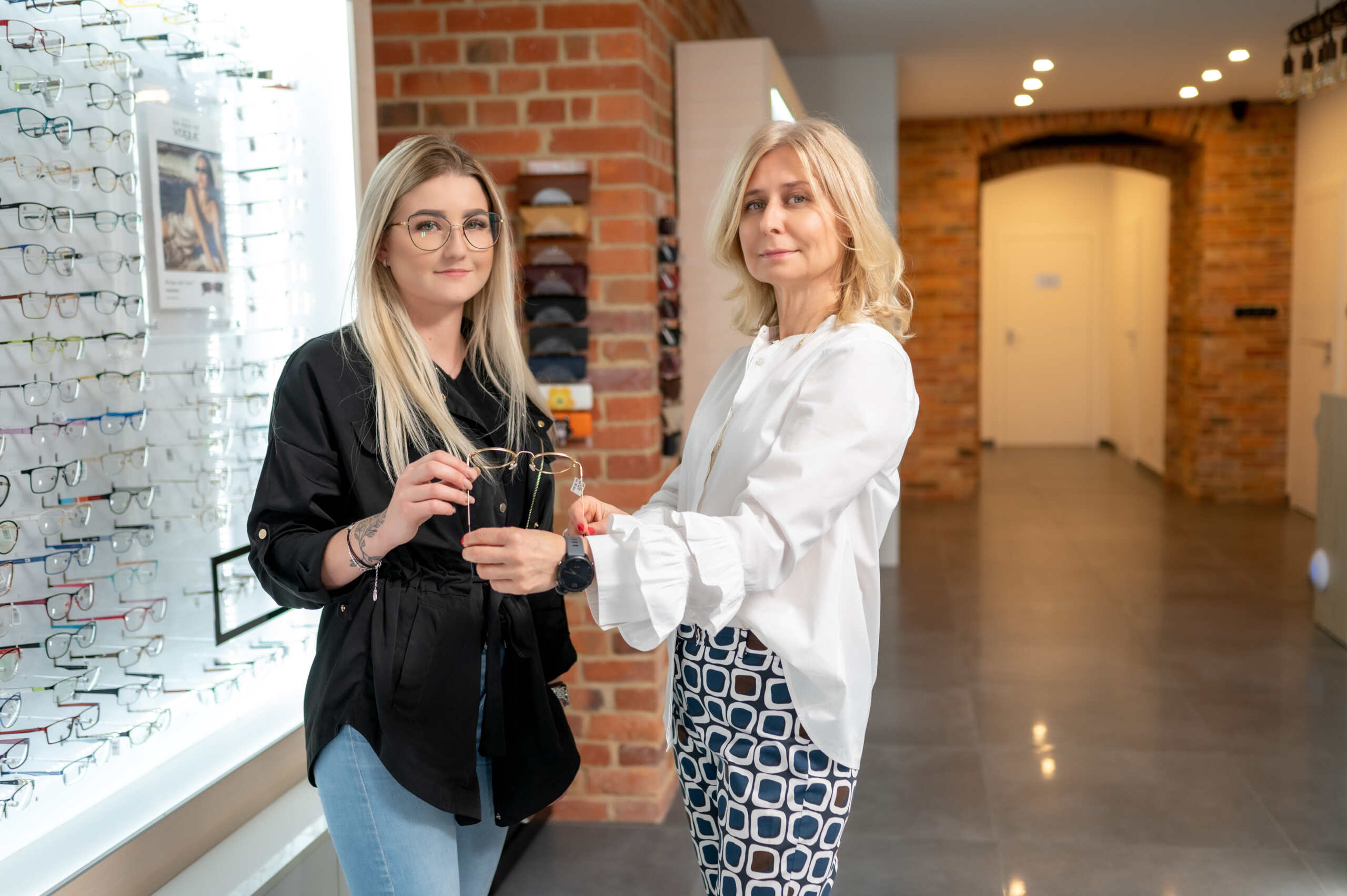 Dobór oprawek okularowych – salon optyczny Świdnica Optometrystka pokazująca klientce oprawki okularowe w salonie optycznym w Świdnicy